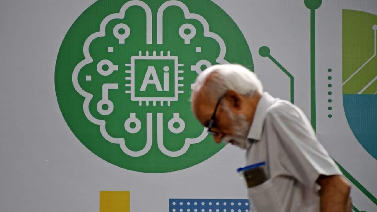 An older man walks past an AI-themed graphic on a wall.