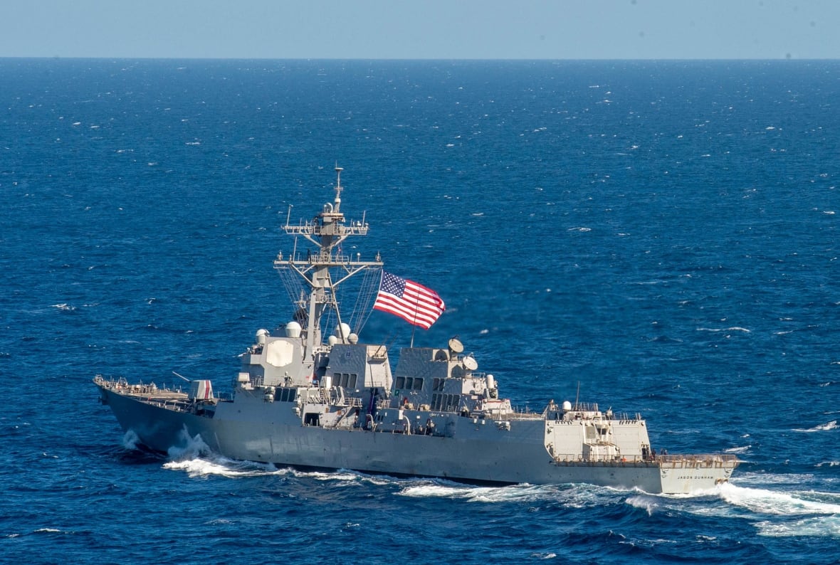 Two navy ships ride the ocean, one with an American flag and another with an Egyptian flag.