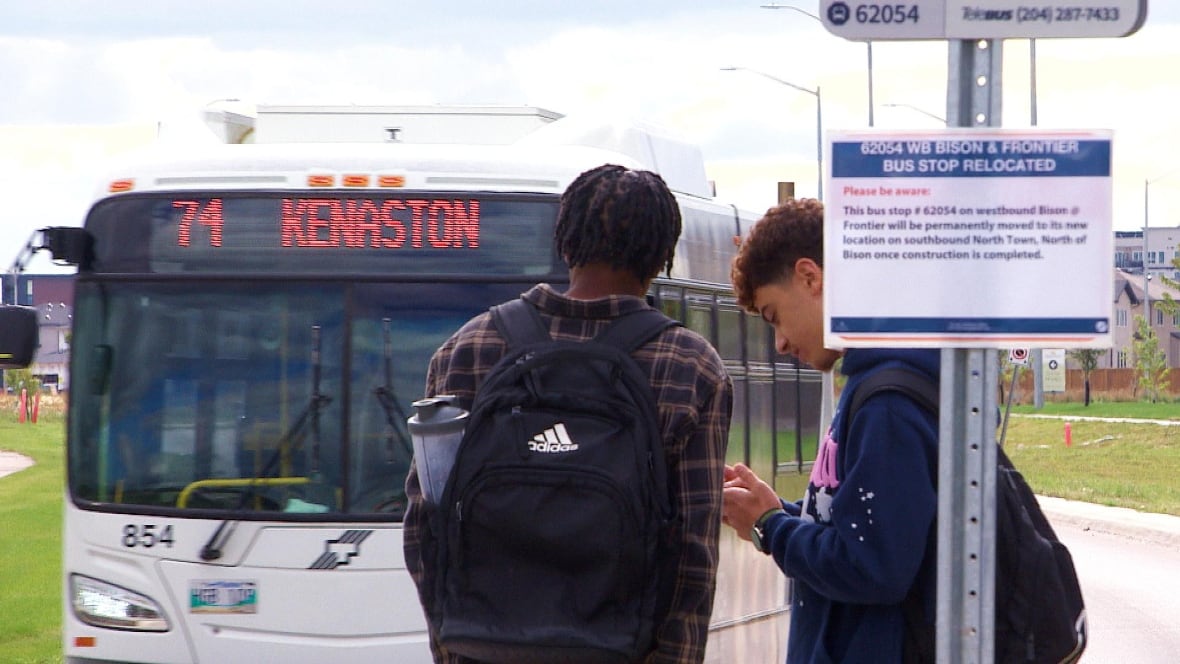 Two students are waiting for the bus, while a bus is arriving in the background.