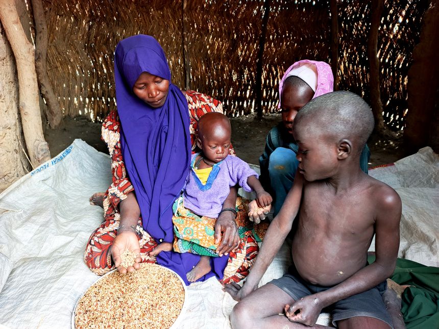 Yagana Usman and her children sit with the last food rations they received from the World Food Programme at the Fulatari camp on September 5, 2025.