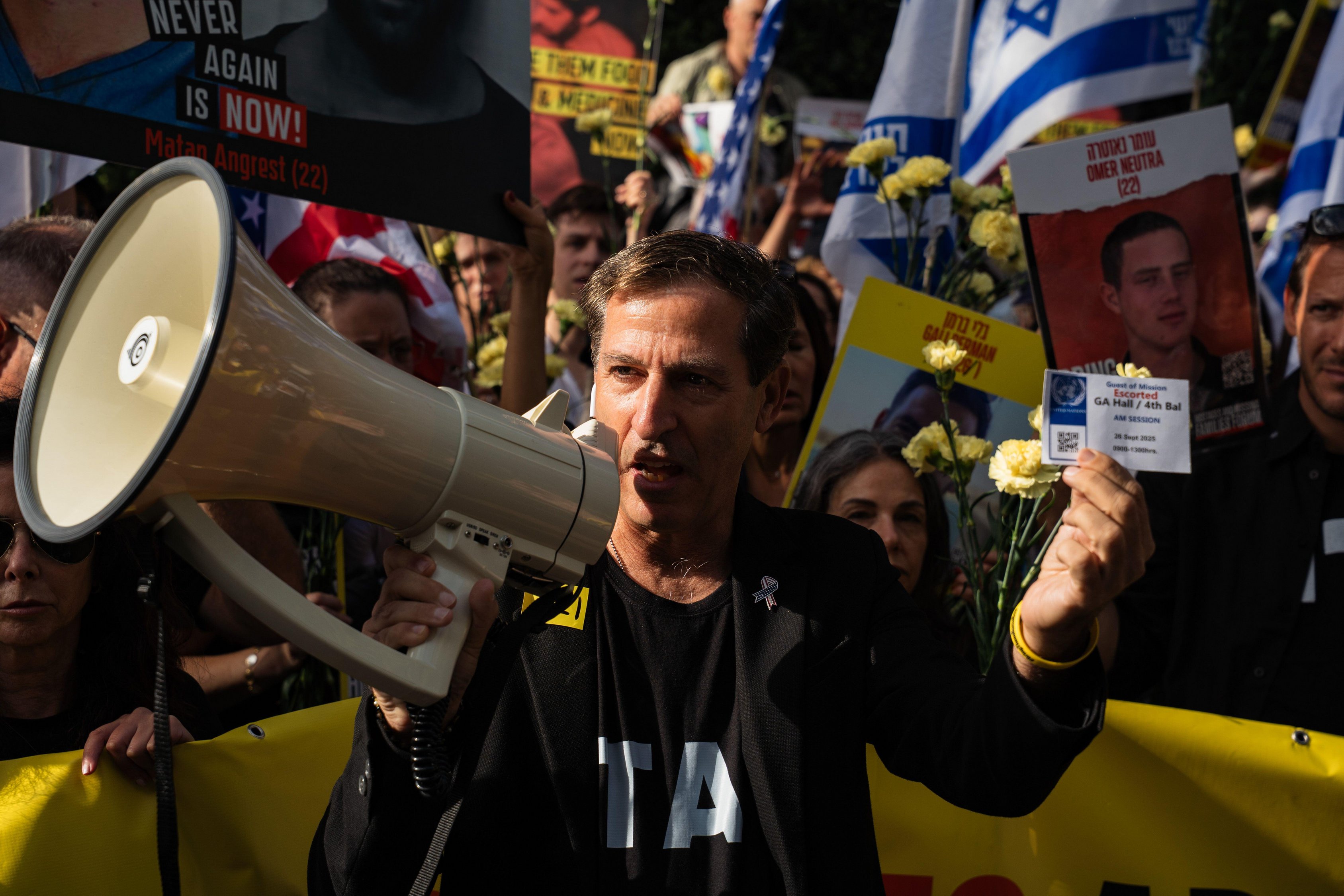 A man with a megaphone holds an invitation to the United Nations while protesting for the return of Israeli hostages.