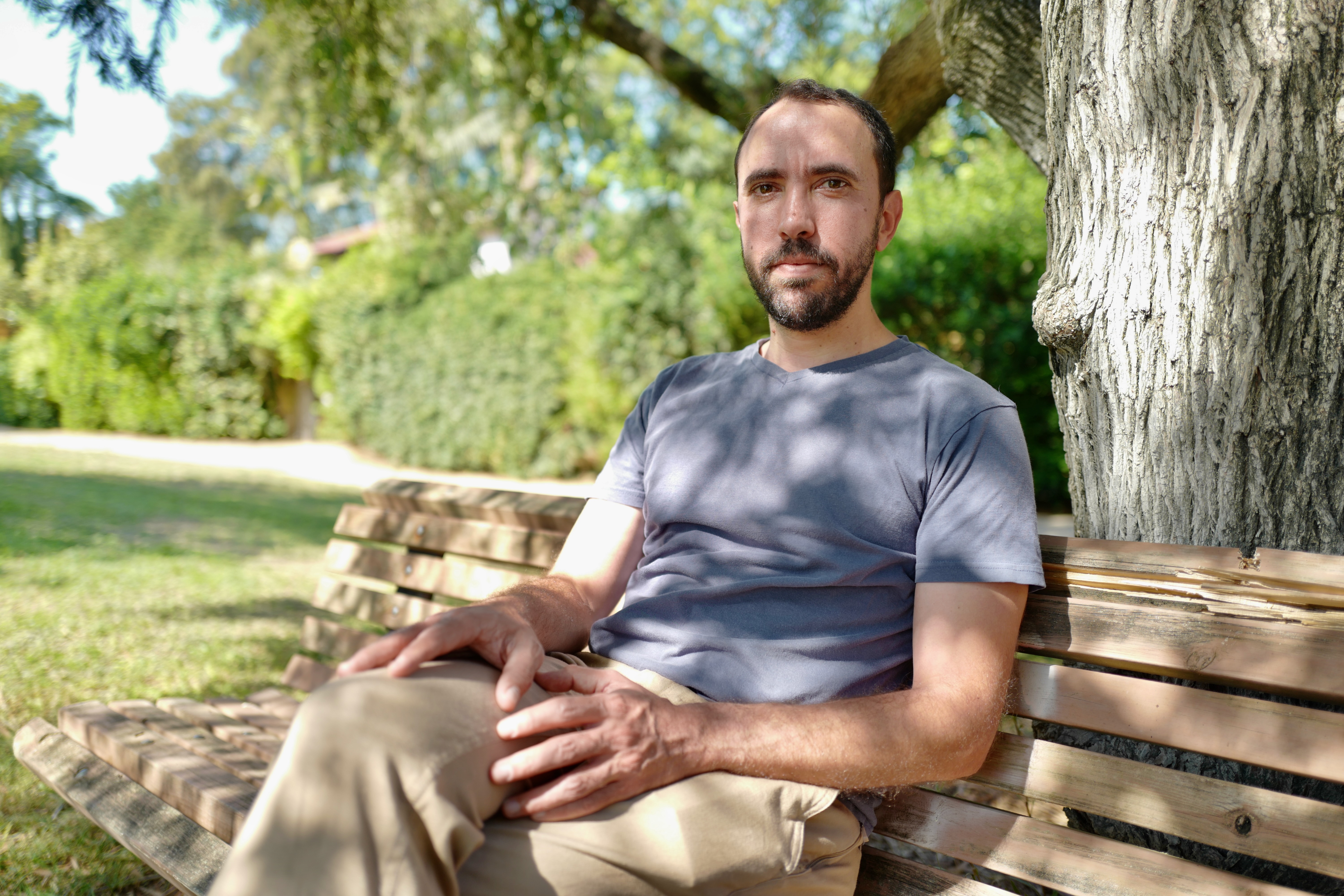 Tal Shoham, an Israeli former hostage, sits on a park bench.