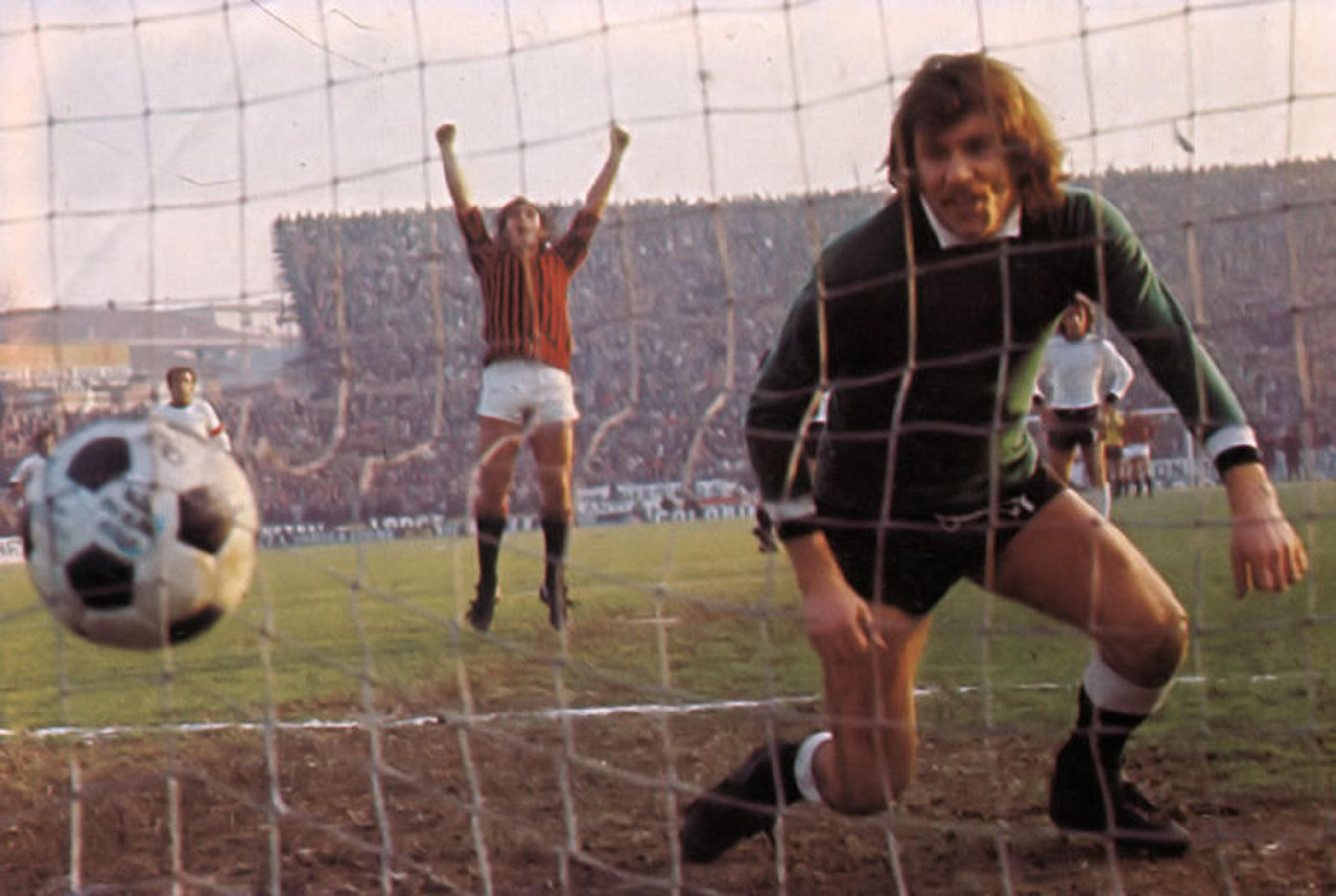 Soccer player Egidio Calloni celebrating a goal while goalie Lamberto Boranga kneels in the net.