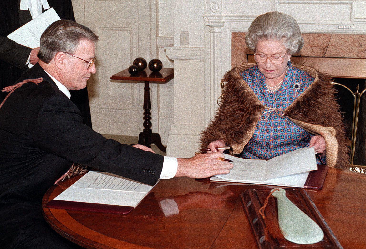 The Queen signs the Waikato Raupatu Claims Settlement Bill in Wellington, attended by James Bolger and Dame Te Atairangikaahu.