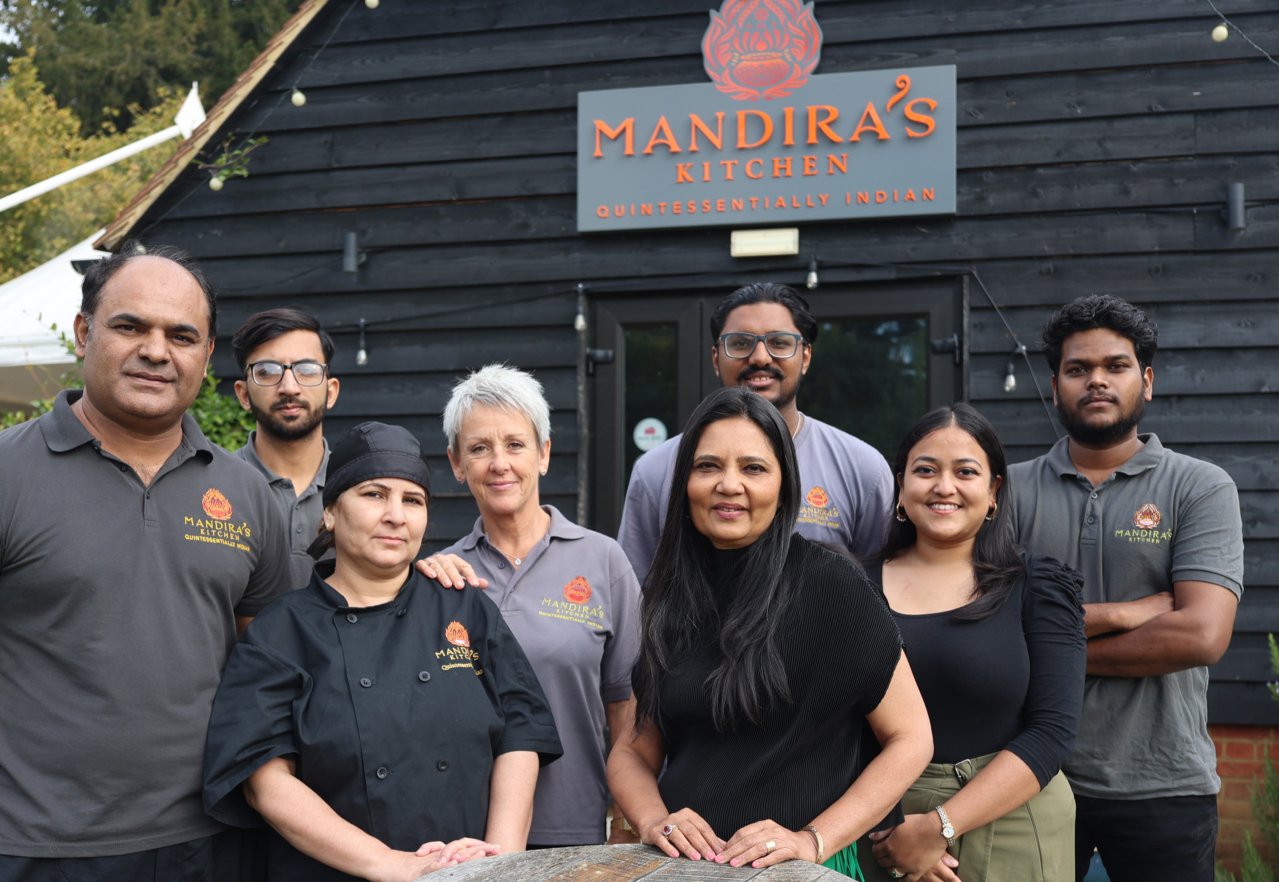 Mandira Sarkar, founder of Mandira's Kitchen, and her staff pose outside her business, Mandira's Kitchen.