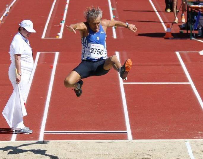 A male long jumper in mid-air, wearing a blue and white singlet with number 2756.