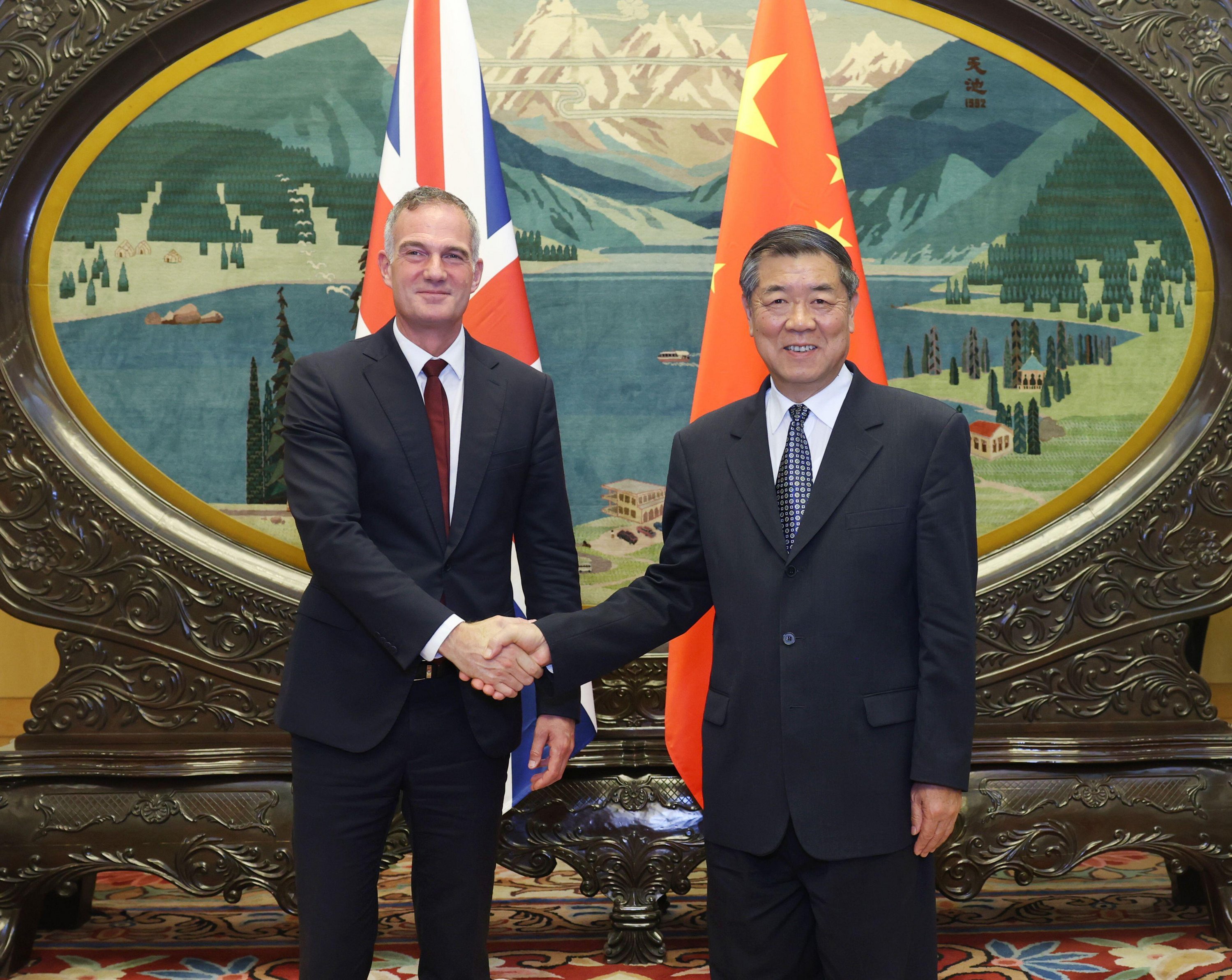 Chinese Vice Premier He Lifeng and British Secretary of State for Business and Trade Peter Kyle shaking hands.