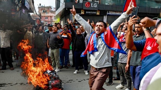People displaying Nepal's national flag burn tyres during a demonstration to condemn the police's deadly crackdown on protesters in Kathmandu