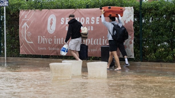 Tourists walk through a flooded street in Ibiza