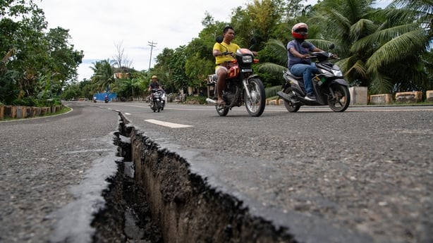 Motorists pass a crack in the road along a major highway in Tabogon town, Cebu province, central Philippines