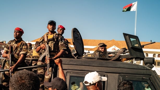 Crowds of people gather to demonstrate as soldiers patrol in Antananarivo