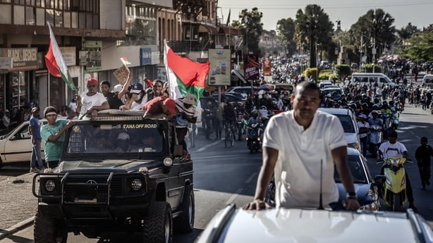 Residents ride in vehicles, waving Malagasy flags and chanting slogans