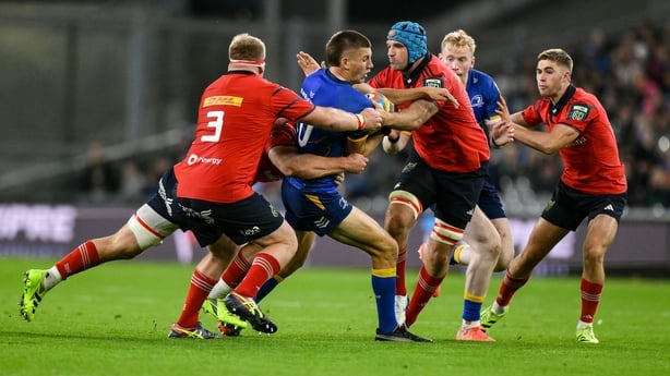 18 October 2025; Sam Prendergast of Leinster is tackled by Munster players, from left, John Ryan, 3, Gavin Coombes and Tadhg Beirne during the United Rugby Championship match between Leinster and Munster at Croke Park in Dublin. Photo by Brendan Moran/Sportsfile