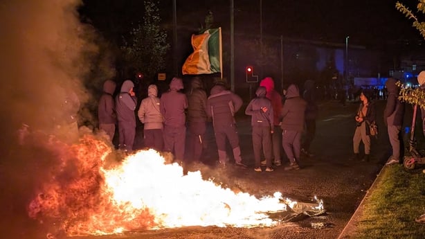 People stand in front of a fire
