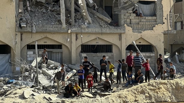 Palestinian residents watch as workers use shovels to remove rubble from the streets of Hamad City, west of Khan Yunis