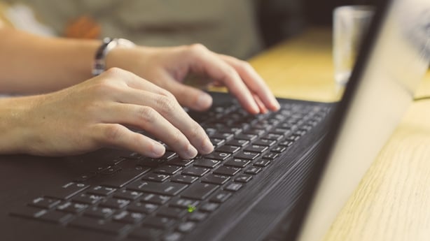 A person typing on their laptop's keyboard 