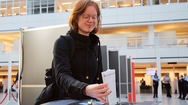 a woman places a ballot sheet in a ballot box after voting