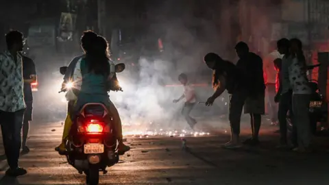 Getty Images People commute on vehicles along a street amid smoggy conditions after Diwali celebrations, the Hindu festival of lights, in Hyderabad, India, on November 1, 2024.