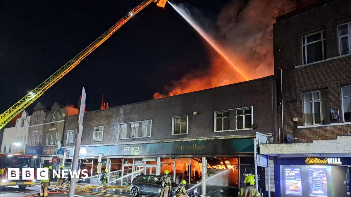A man raises his fist while standing in front of a group of people waving flags, including saltires and a union flag.