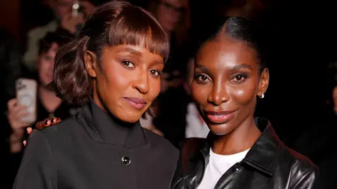 Getty Images Ayo Edebiri wore a black funnel-neck buttoned jacket, while Michaela Coel donned a white T-shirt and black 70s style leather-look jacket