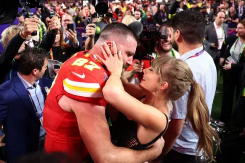 Getty Images Travis Kelce and Taylor Swift embracing at a football match