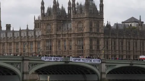 PA Media Protesters unfurl a banner on Westminster Bridge as part of a demonstration organised by Defend our Juries