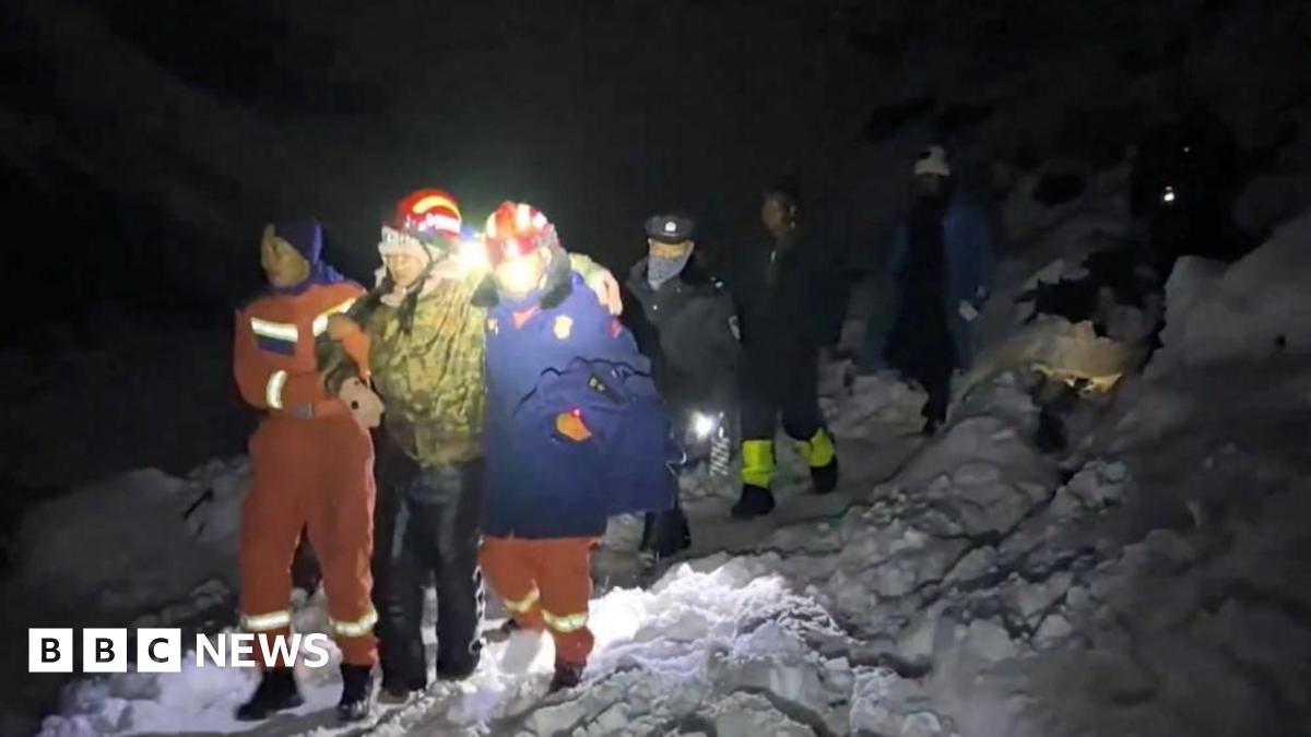 A hiker is supported by two rescue staff as he makes his way down a snowy slope on Mount Everest.