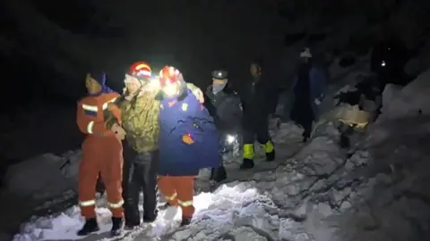 Reuters A hiker is supported by two rescue staff as he makes his way down a snowy slope on Mount Everest.