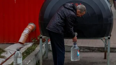 Reuters A man fills a plastic bottle with water from a tank located outdoors.