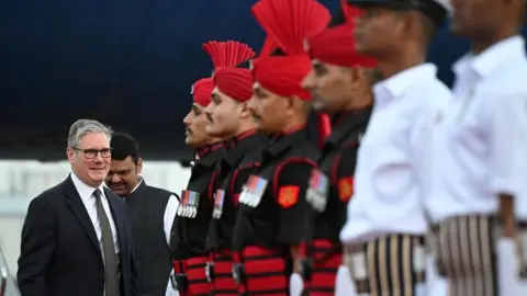 Reuters Soldiers in Indian uniform stand to attention as British Prime Minister Sir Keir Starmer leaves his plane in India.