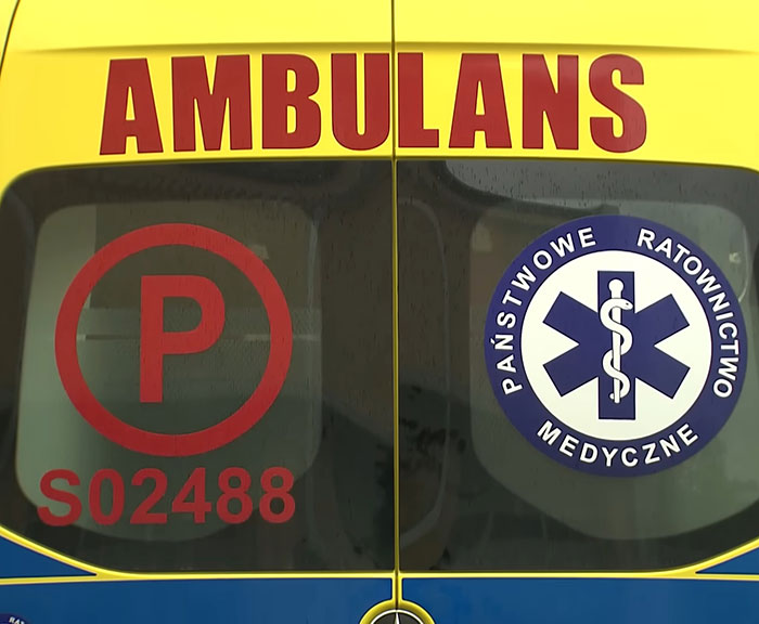 Rear view of an ambulance with emergency medical service logos and red lettering on yellow background.