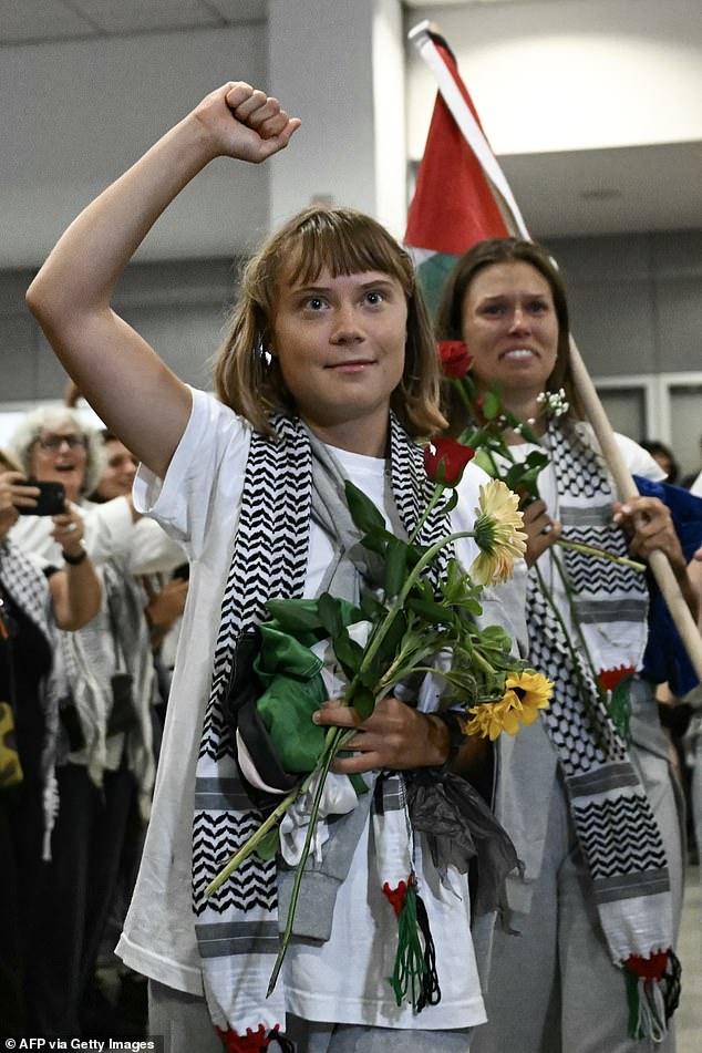 Swedish climate campaigner Greta Thunberg raises her fist, upon arrival alongside activists who were sailing aboard vessels from the Gaza-bound aid flotilla before being stopped and detained by Israeli forces, greeted by a crowd of supporters, at the arrivals area of Athens International Airport on October 6, 2025