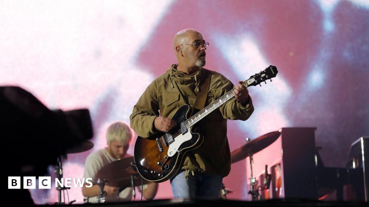 Bonehead performing on stage with Oasis