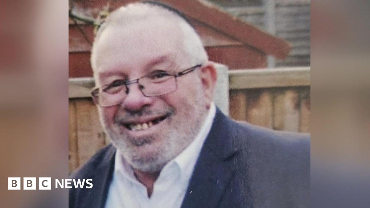 Melvin Cravitz smiles. He is wearing a dark kippah hat, glasses and a dark suit jacket with a white shirt.