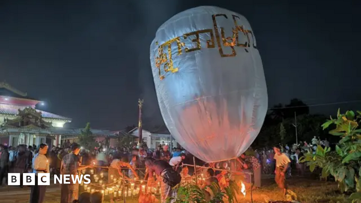 People lighting candles in the night time around a giant white balloon