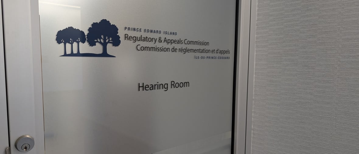 A metal framed door with frosted glass with the words Prince Edward Island Regulatory & Appeals Commission Hearing Room.