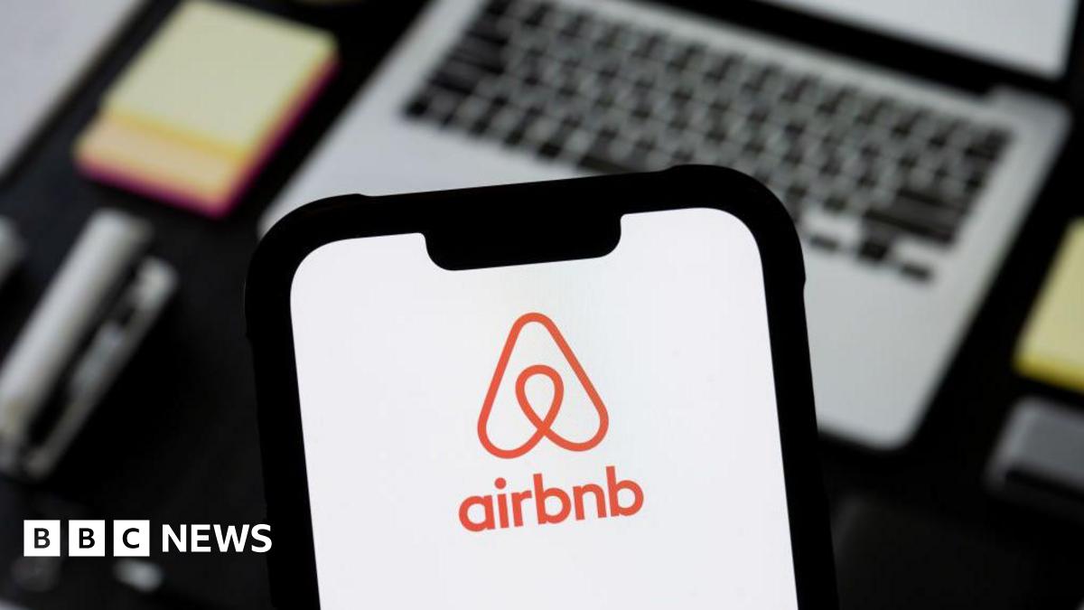 A phone with the Airbnb app is depicted in the foreground, and laptop is pictured in the background