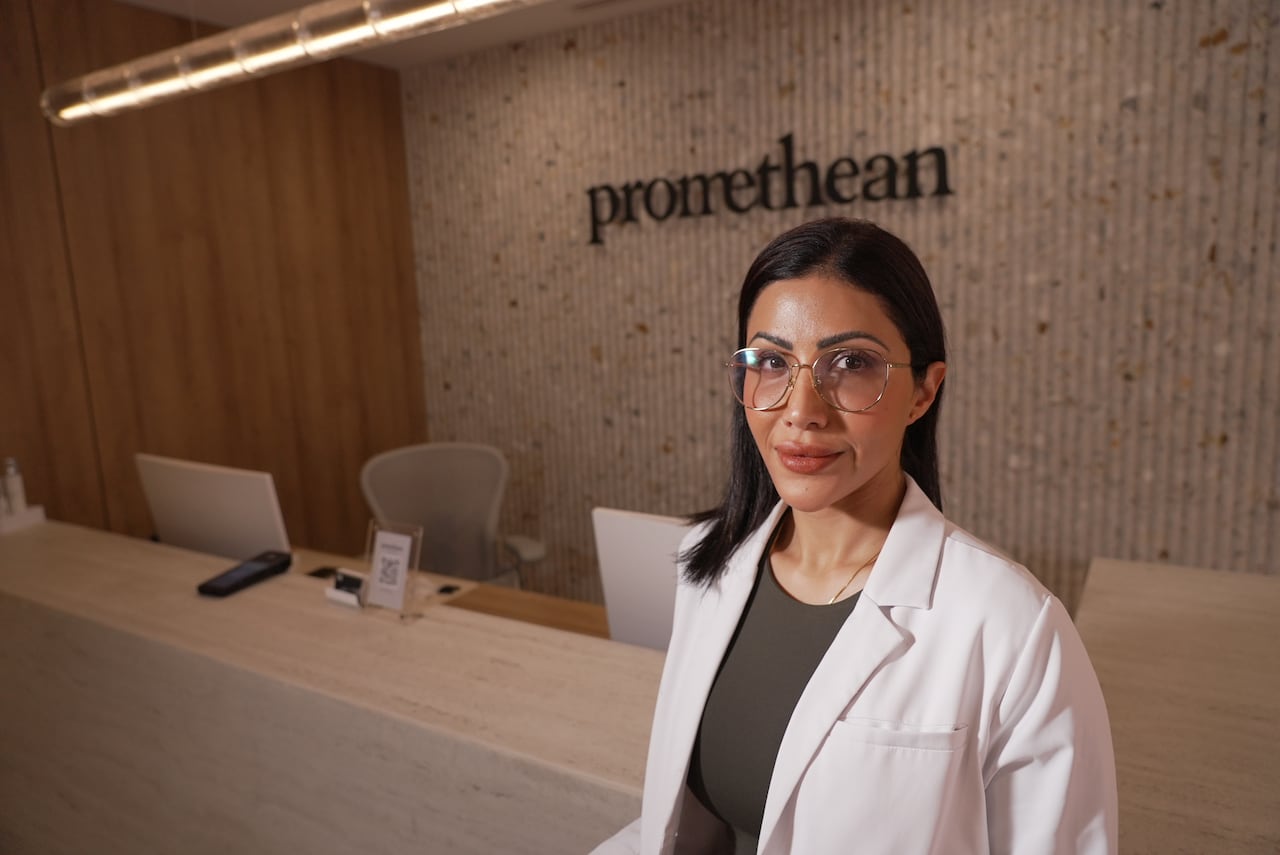 A woman in a white lab coat looks at camera. 