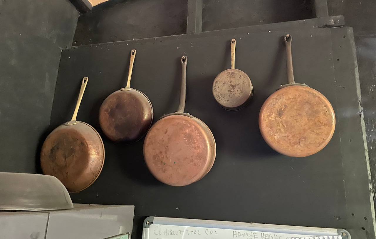 Five pans hang on a wall