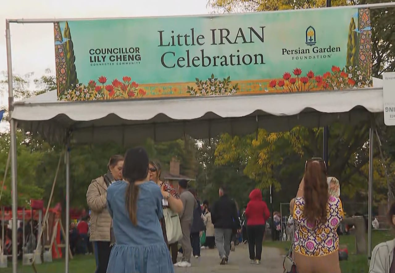 Sign marking entrance to Little Iran celebration, people taking pictures in front of sign