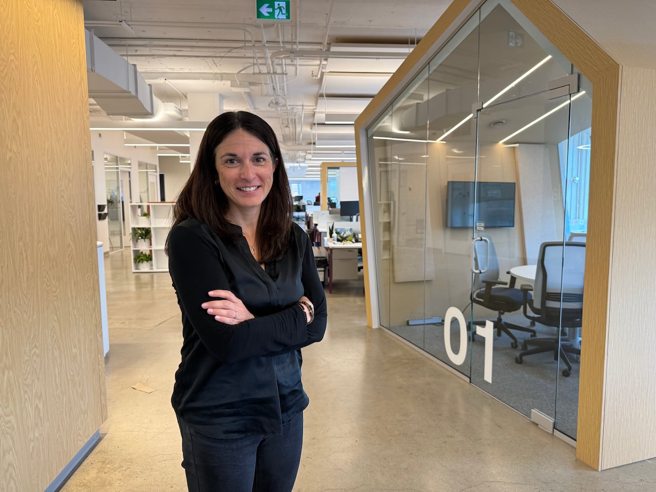 A woman with dark brown hair stands inside a tech office.