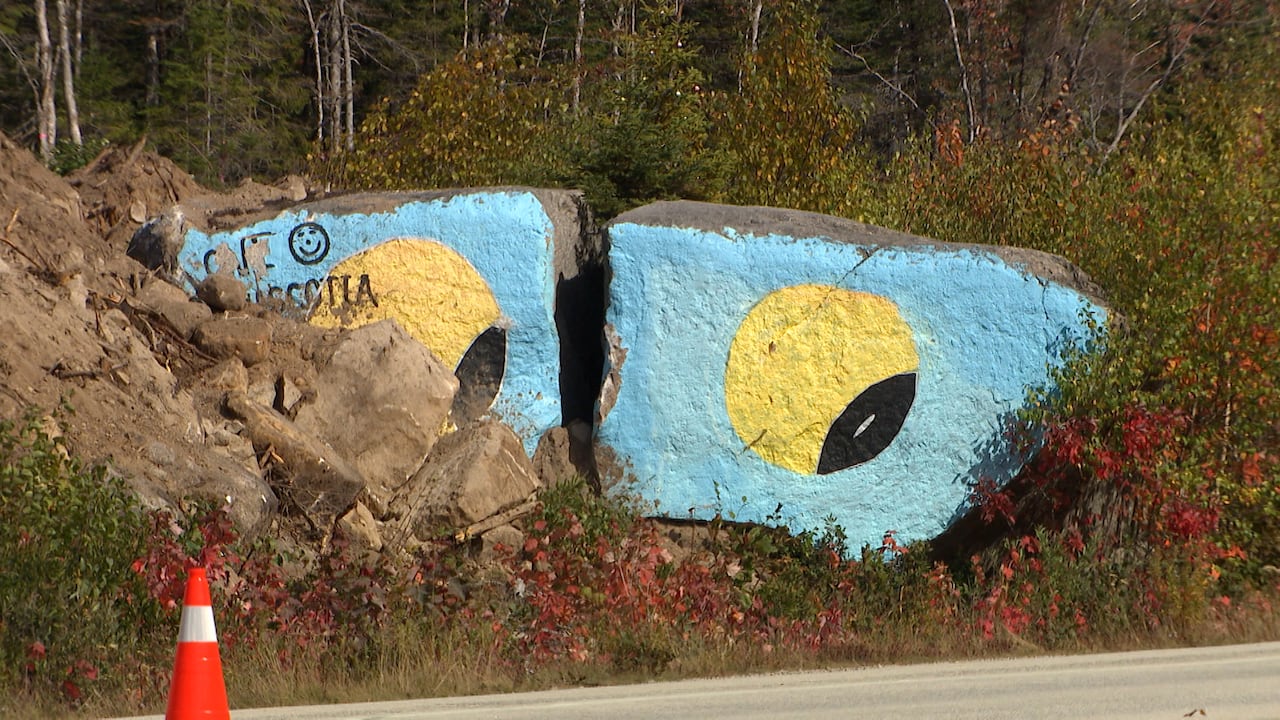 Two large rocks on the side of the road are painted as eyes. 