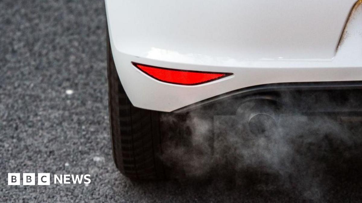 A close up of a white car's exhaust pipe emitting fumes