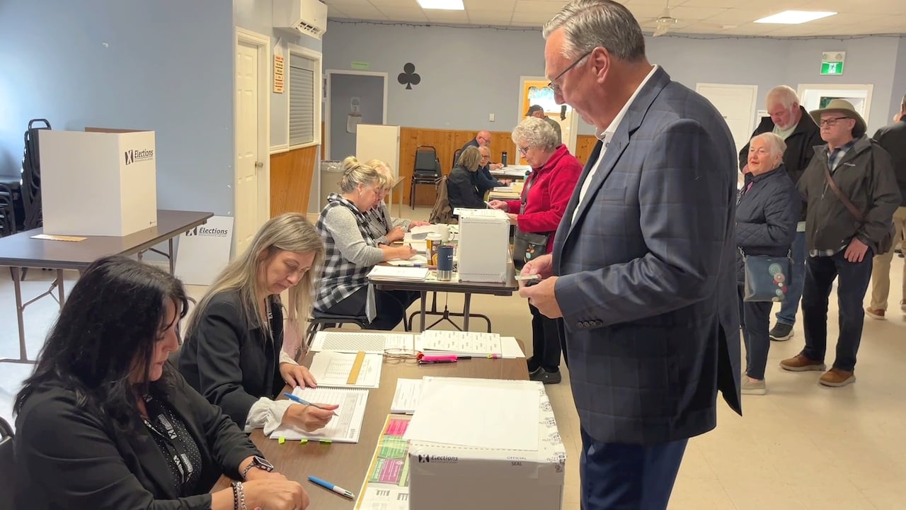 Tall man in suit standing inside polling station waiting to vote