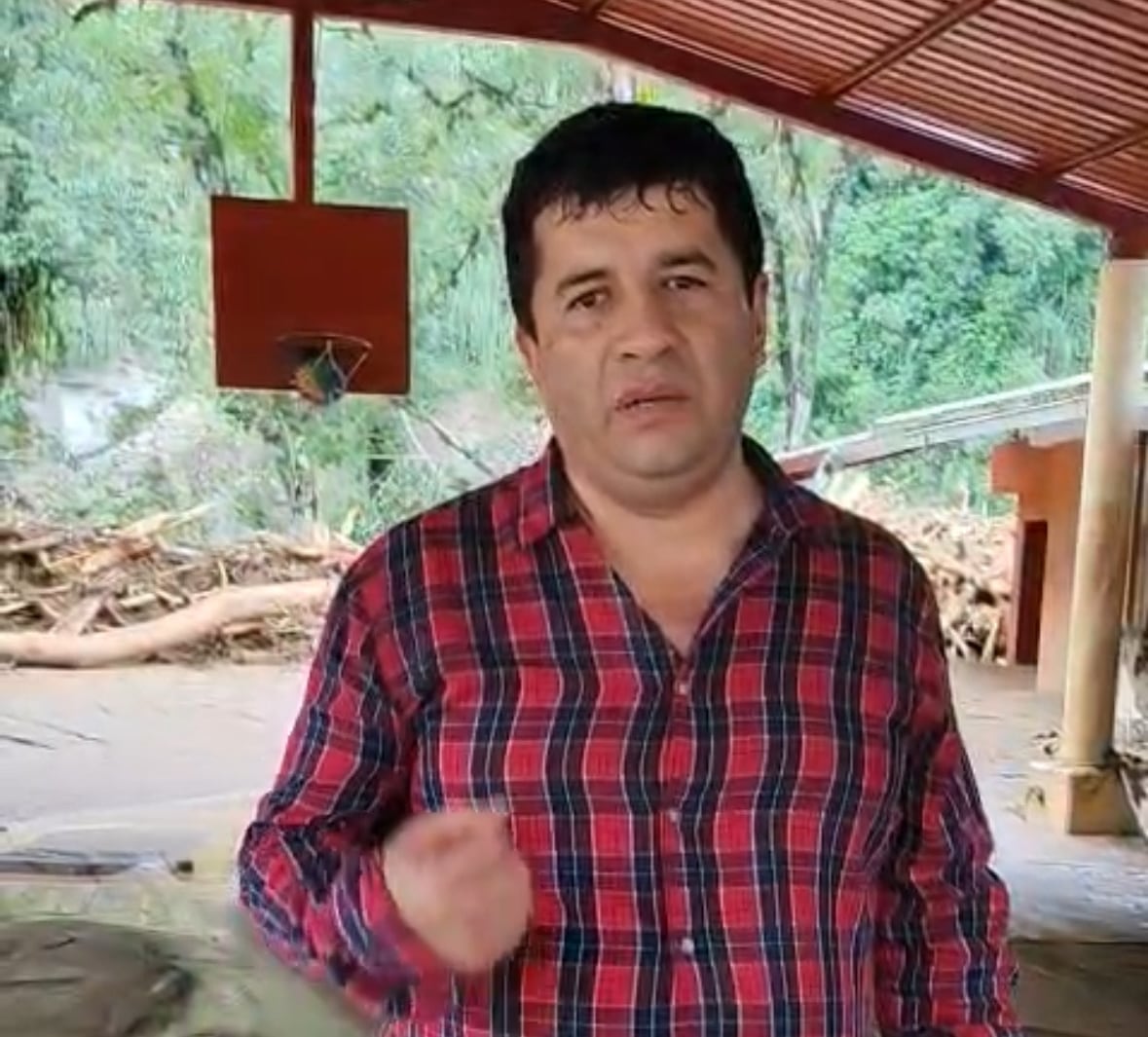 A dark-haired man wears a plaid shirt.