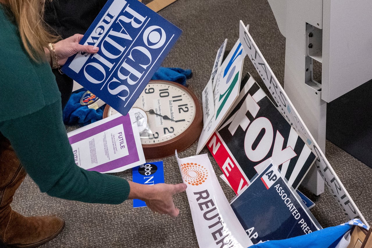 Signs and logos from various news outlets are collected from the floor
