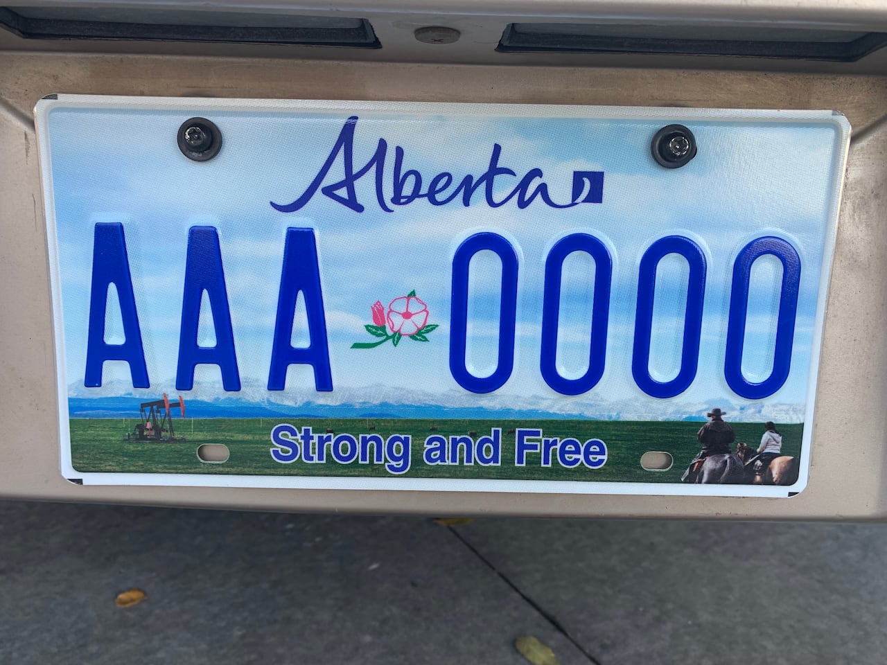 A licence plate with a design including mountains in the background, and pumpjacks, and cowboys in the foreground
