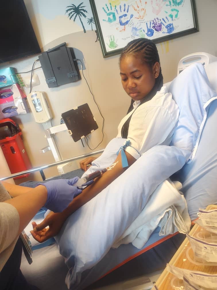 Giril in hospital robe having blood drawn from arm