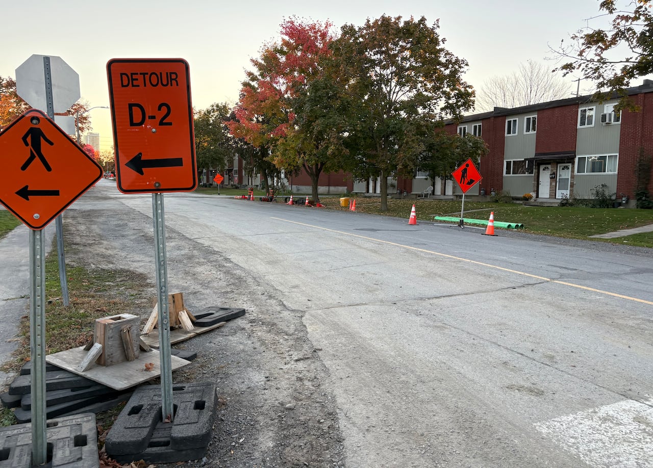 A residential city road with orange construction signs.