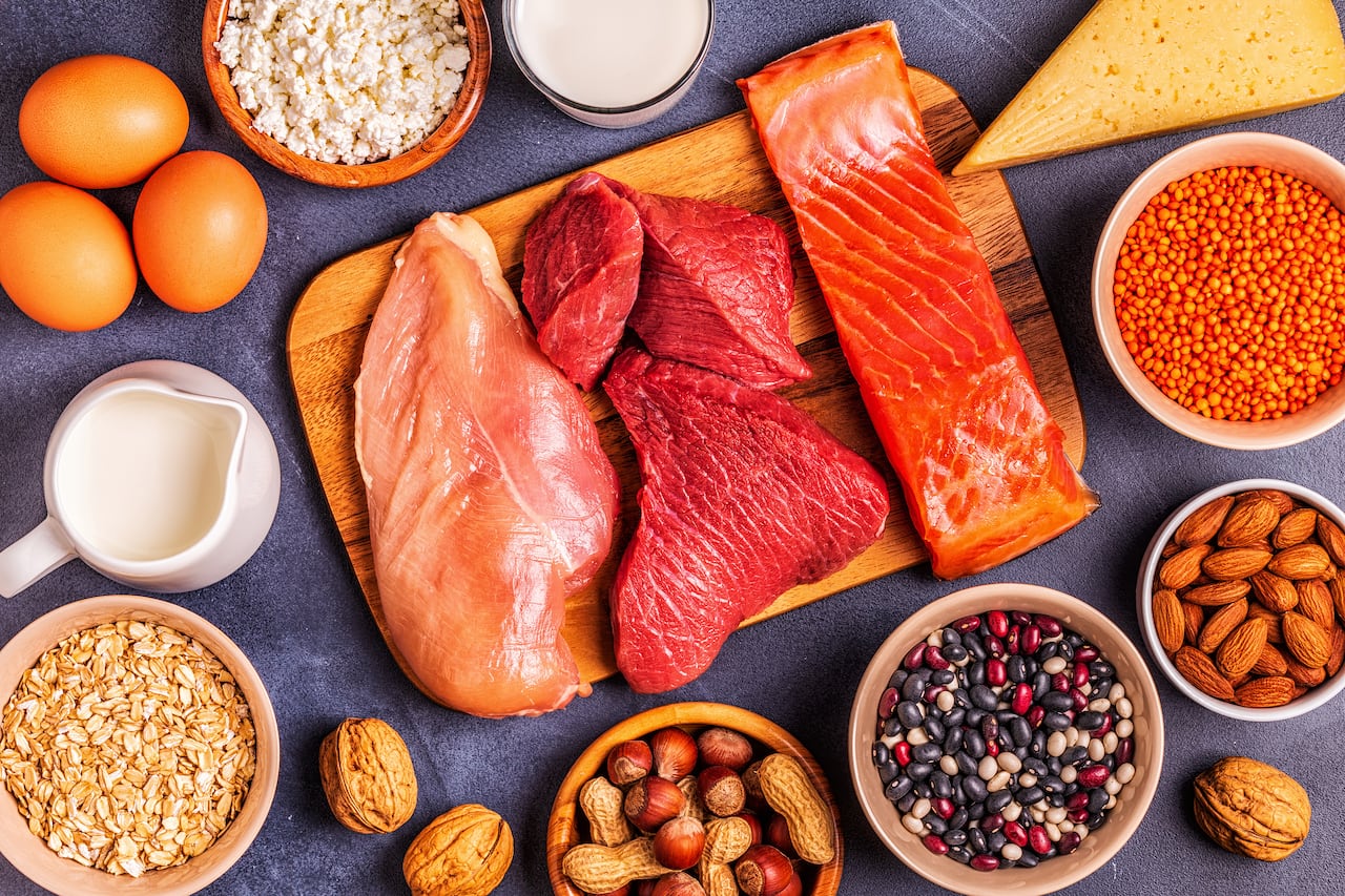 Protein-rich foods like meat, nuts, cheeses and eggs on a table and board. 